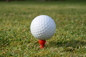 a golf ball on a red tee waiting to be hit.