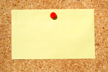 a yellow note held on a cork notice board with a r