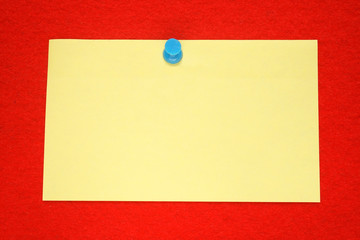 a yellow note held on a red felt notice board.