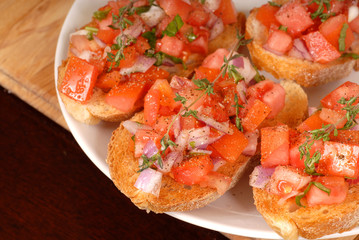 tomato and onion bruschetta with thyme on cutting board