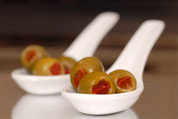 low view of green stuffed olives in white spoons