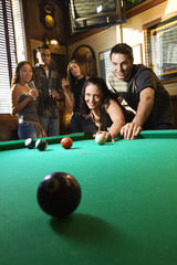 group of young adults playing pool.