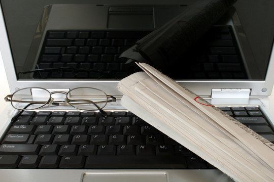 laptop with newspaper and eyeglasses