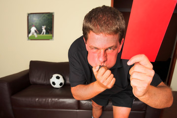 referee in sitting room blowing whistle with red c