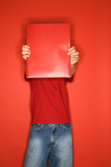 caucasian boy covering face with folder.