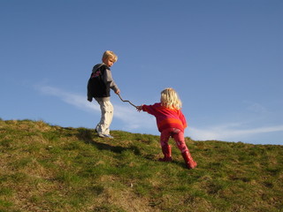 Little girl reaching out for help from her older, helpful brother