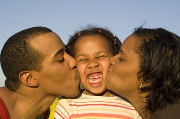 parents kissing their cute daughter