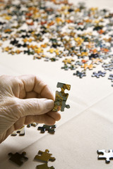 elderly caucasian woman's hand holding puzzle piece.