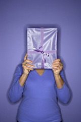 Woman holding present in front of face.