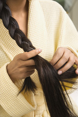 Young woman braiding hair.