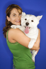 Woman holding white terrier dog.
