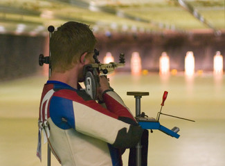 olympics shooter resting between shots with the targets illuminated on an indoor range