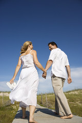 Fototapeta na wymiar Couple holding hands walking down path.