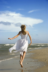 Fototapeta na wymiar Pre-teenage girl running down the beach.