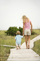 Girl walking on beach walkway with little boy.