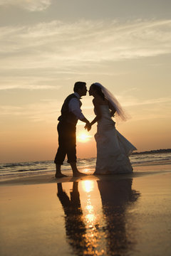 Bride and groom kissing on beach.