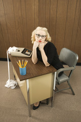 woman sitting at desk with chin on her fists.