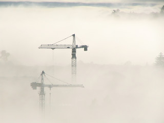 tower cranes protruding through fog