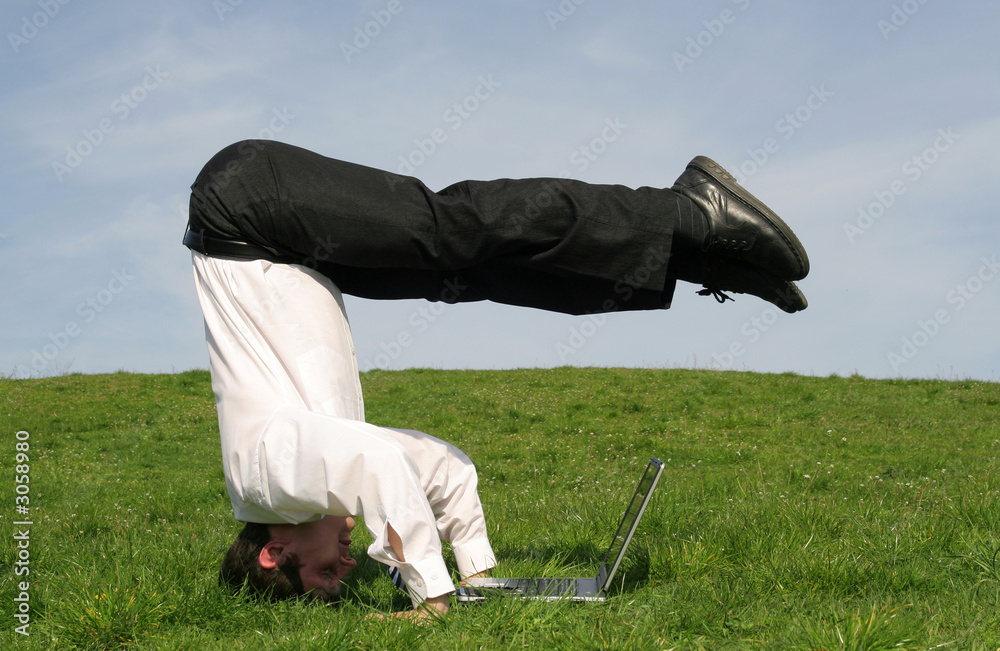 Wall mural businessman upside down using laptop