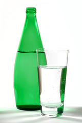 glass of mineral water and green bottle