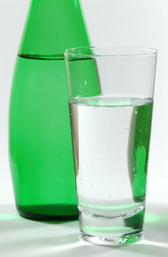 glass of mineral water and green bottle