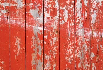 red flaky paint on a wooden fence.