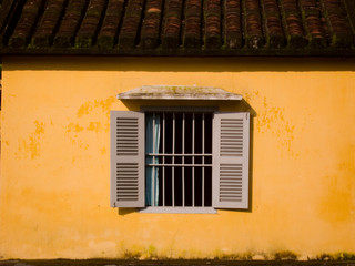 shuttered window in yellow wall