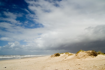 large dunes agains dark blue skies with some bright clouds