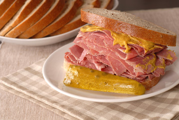 corned beef sandwich with mustard and pickle on rye