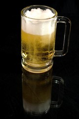 mug of beer reflecting on black surface