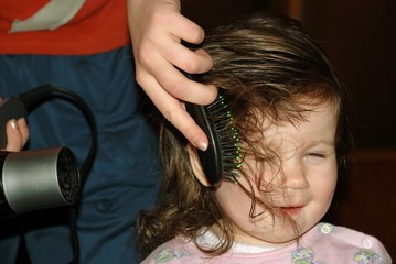 Fototapeta premium drying of hair by a hair drier to the little girl