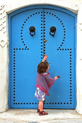 child knocking on a blue door - tunisia