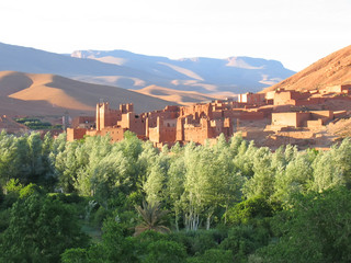 moutain with sand dunes and a fortress in an oasis on the foregr