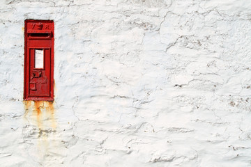 an english victorian post box in a white wall.