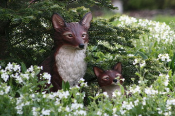 two ceramic foxes in a garden