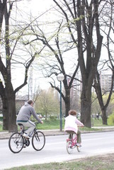 father and daughter riding bike in park