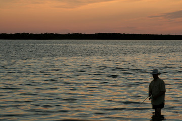Fototapeta na wymiar lone fisherman in water at sunset