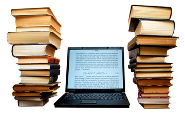 Two large piles of books next to  laptop