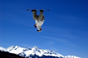 inverted snowboarder flying over a peak