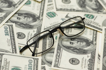 reading glasses over hundred dollar bank notes