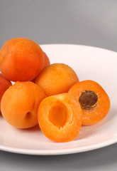 several apricots on a white plate - vertical