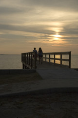 two people on a dock looking at sunset