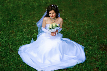 beautiful bride sitting on green grass