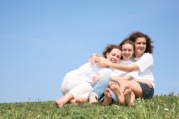 Three girlfriends in white T-shorts embrace