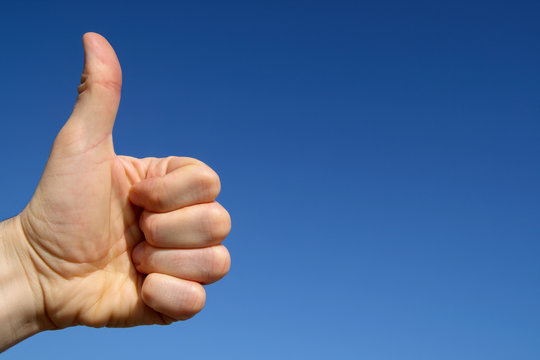thumbs up with blue sky background and space for t