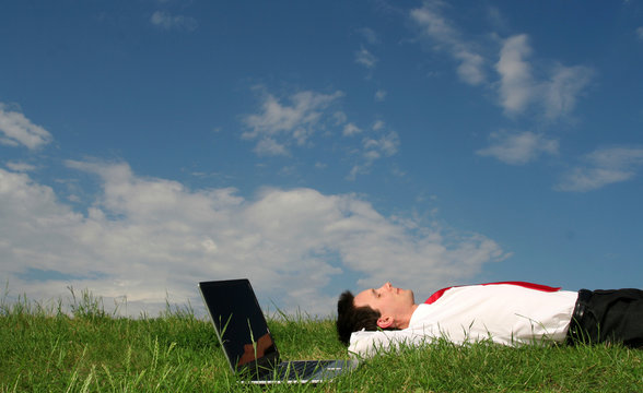 man lying on the grass with laptop