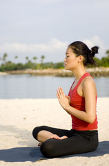 Fototapeta na wymiar A young woman practising yoga on the beach