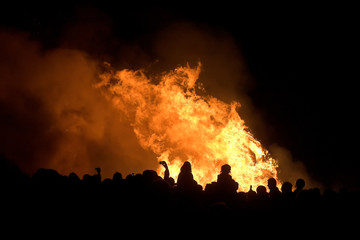 siluetas de gente frente al fuego, noche de San Juan - obrazy, fototapety, plakaty