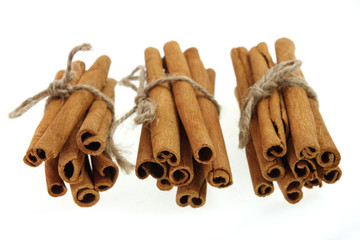 three bunches of cinnamon sticks, tied by rope. soft focus.