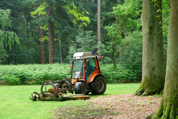 Lawn mower machine mowing the lawn in a formal garden